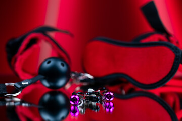 erotic bdsm toys for intimate sexual games nipple clamps for girls on the background of a red blindfold and handcuffs