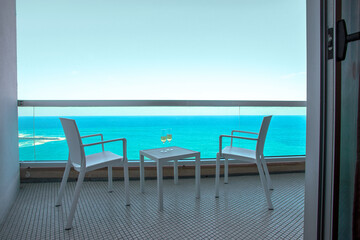 Fototapeta na wymiar Romantic vacation cocnept. Two wine glass eson the table in hotel balcony with sea view in tropical country.