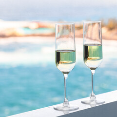 Concept for romantic vacation. Two champagne glass on hotel balcony with beautiful ocean view in  tropical country.