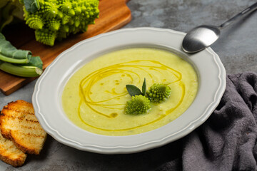 Eating creamy romanesco broccoli soup and toasted bread. Vegan dish. Fresh roman broccoli on...
