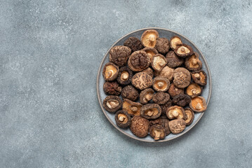 Dried shiitake mushrooms on a plate, gray concrete grunge background. Top view, flat lay. Asian food.