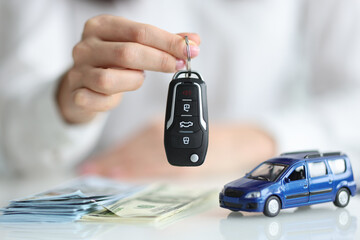 Dealer holding keys in front of toy car and money closeup