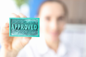 Woman holding green ink stamp approved closeup