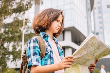 Hipster young girl travels around the city. Cute brunette teen girl looks at the map. Traveling in summer vacation. City travel and tour.