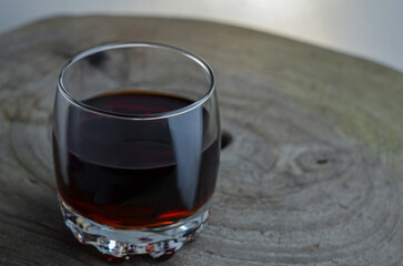 Red, dark wine on a wooden tray in a glass glass in a soft background lighting. Dark photo of red wine in soft shadows.