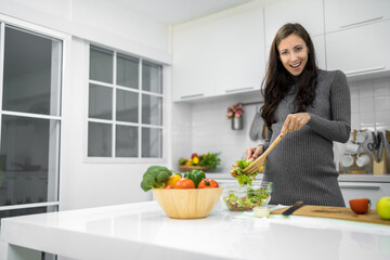 Healthy European pregnant woman cooking healthy salad at home kitchen smiling and happy
