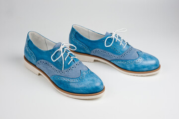 Blue imitation leather shoes laced with white laces. Close-up shot.