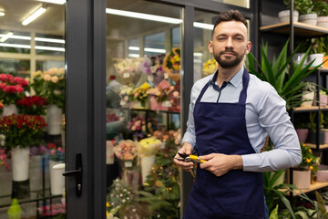 male florist on the background of the refrigerator with flowers and bouquets