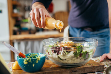 close up man dressing salad. preparing food in his kitchen