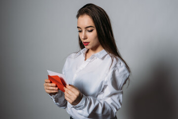 Naklejka premium Valentines Day, romance, dating concept, copy space. Young beautiful girl reads a valentine greeting card in red envelope