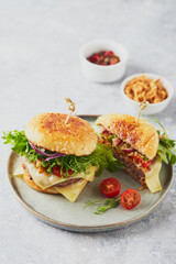 Two burgers with veal cutlet and herbs on wooden cutting board