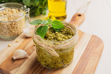 Homemade basil pesto sauce with ingredients in the glass jar
