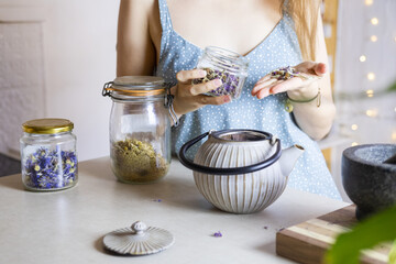 Close up photo of woman hands preparing a herbal tea in a kitchen.