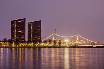 Fototapeta na wymiar Rotterdam, The Netherlands, January 24, 2022: view across the river Nieuwe Maas during the blue hour towards residential towers at Katendrecht and the former cruiseship SS Rotterdam
