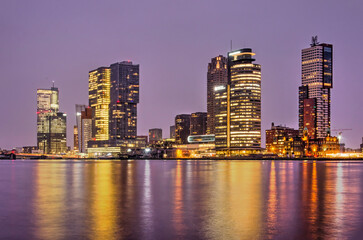Fototapeta na wymiar Rotterdam, The Netherlands, January 24, 2022: the modern highrise on Wilhelminapier reflecting in the river Nieuwe Maas during the blue hour in the morning