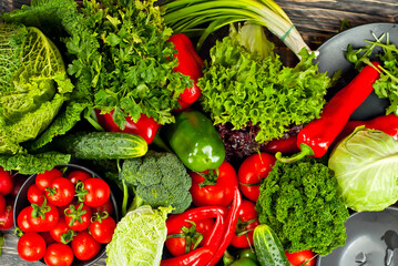 Cabbage, peppers, tomatoes, cucumbers, lettuce, cherry tomatoes, broccoli, arugula on a black background. variety of vegetables on a pile on a wooden table.