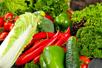Cabbage, peppers, tomatoes, cucumbers, lettuce, cherry tomatoes, broccoli, arugula on a black background. variety of vegetables on a pile on a wooden table.