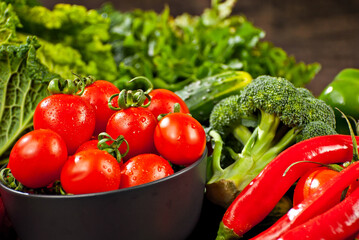 Cabbage, peppers, tomatoes, cucumbers, lettuce, cherry tomatoes, broccoli, arugula on a black background. variety of vegetables on a pile on a wooden table.