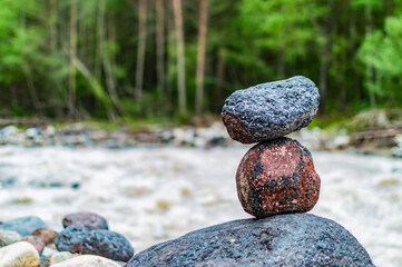 Fototapeta na wymiar A pyramid of stones against the background of a bubbling river