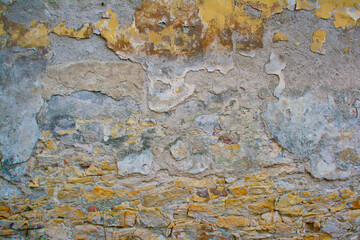 An old wall with partially collapsed paint and an unusual multicolored texture. Natural background with layers of different colors.