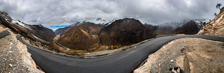 Panoramic image of a road crossing the highest part of the Andes mountain range, with the Huascaran mountain in the background, in Ancash, Peru