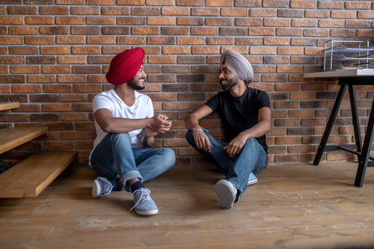 Two young men sitting on the floor at home and looking relaxed