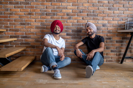 Two young men sitting on the floor at home and looking relaxed