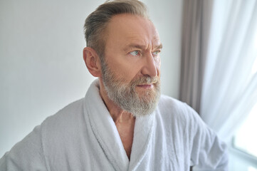 Obraz premium Thoughtful man in the towelling robe looking away