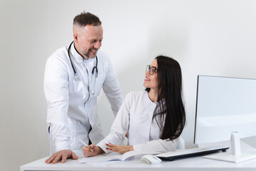 Young female medical worker consults with the male head physician. Two doctors colleagues having...