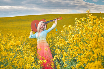 Fototapeta premium sexy woman in the field with a guitar. concept freedom, inspiration, relaxation