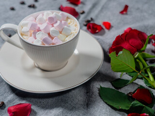 Coffee in a white cup and marshmallows. with a rose on a brown background..The concept of congratulations, Valentine's Day, mother's day