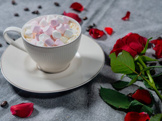 Coffee in a white cup and marshmallows. with a rose on a brown background..The concept of congratulations, Valentine's Day, mother's day