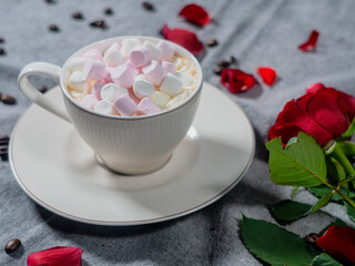 Coffee in a white cup and marshmallows. with a rose on a brown background..The concept of congratulations, Valentine's Day, mother's day