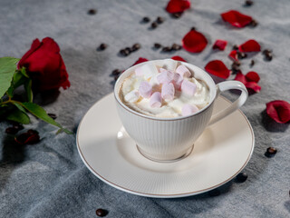 Coffee in a white cup and marshmallows. with a rose on a brown background..The concept of congratulations, Valentine's Day, mother's day