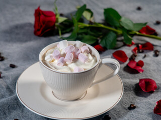 Coffee in a white cup and marshmallows. with a rose on a brown background..The concept of congratulations, Valentine's Day, mother's day