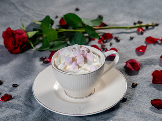 Coffee in a white cup and marshmallows. with a rose on a brown background..The concept of congratulations, Valentine's Day, mother's day