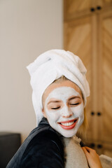 Young woman with face mask laughing while sitting in bed