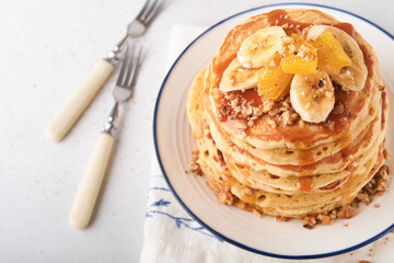 Pancakes. Homemade fluffy pancake with banana, walnut and caramel for breakfast on light concrete background. Delicious pancakes for traditional American breakfast. Selective focus. Mock up.