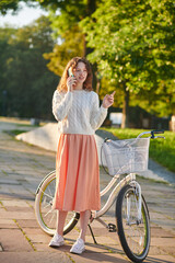 Fototapeta na wymiar Girl in pinky skirt with a bike in the park