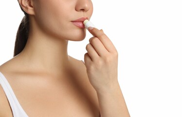 Obraz na płótnie Canvas Young woman applying lip balm on white background, closeup
