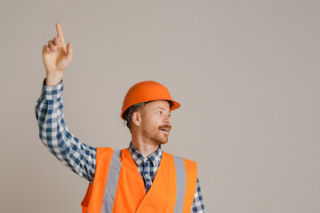 White man worker wearing helmet pointing finger upward