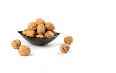Walnuts in a dark plate on a white background.Copy space.