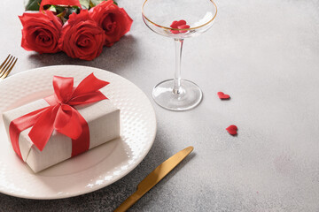Valentine's day dinner with romantic gift and red roses on gray background. Close up. Copy space.