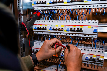 Electrician performing power tests on switches and differentials for the light of an industrial...