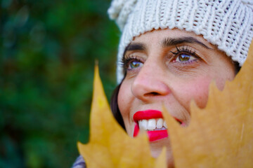 Close-up portrait of young elegant woman in autumn season with a leaf.