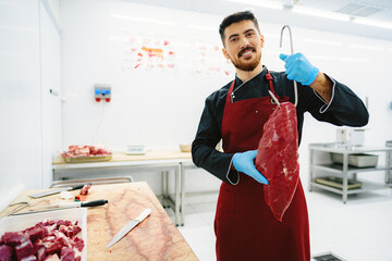 Butcher man holding meat on hook to cut and sell it