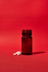 A pill bottle with medicinal pills on a red background. Isolated