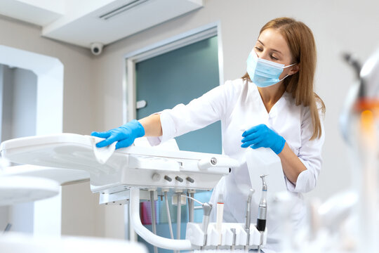 Dentist assistant wipes dental equipment in office