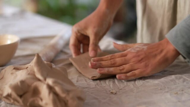 Woman hands rolling out clay with a rolling pin at home