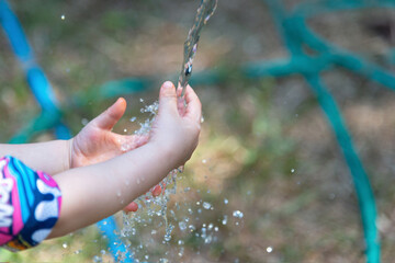 The little boy's hand is played with a hose in a sunny backyard. Preschoolers are fun with water...